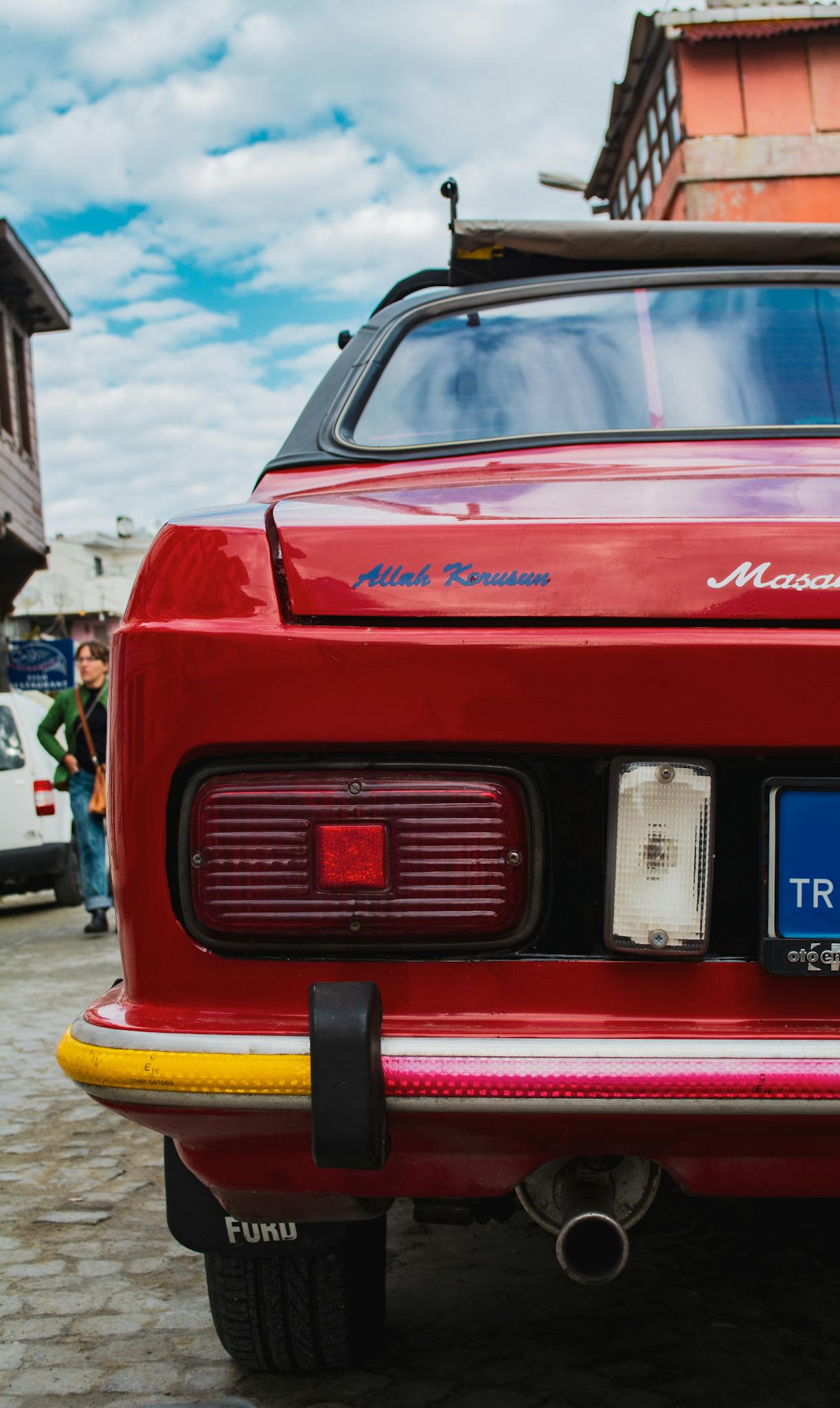 A stylish classic red car with vintage details parked in a historical area.