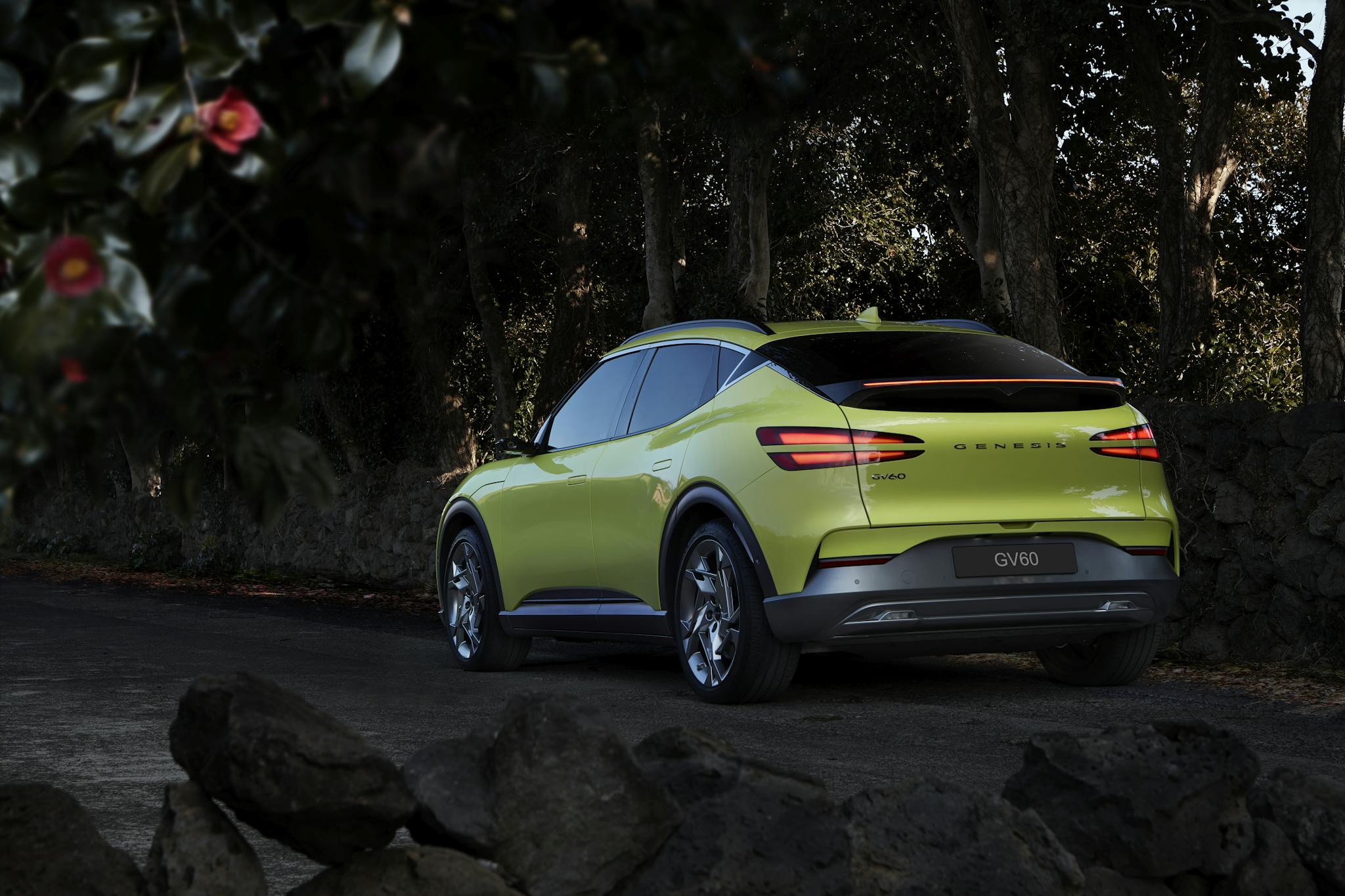 Capture of a luxury Genesis GV60 electric car parked on a winding road surrounded by nature.