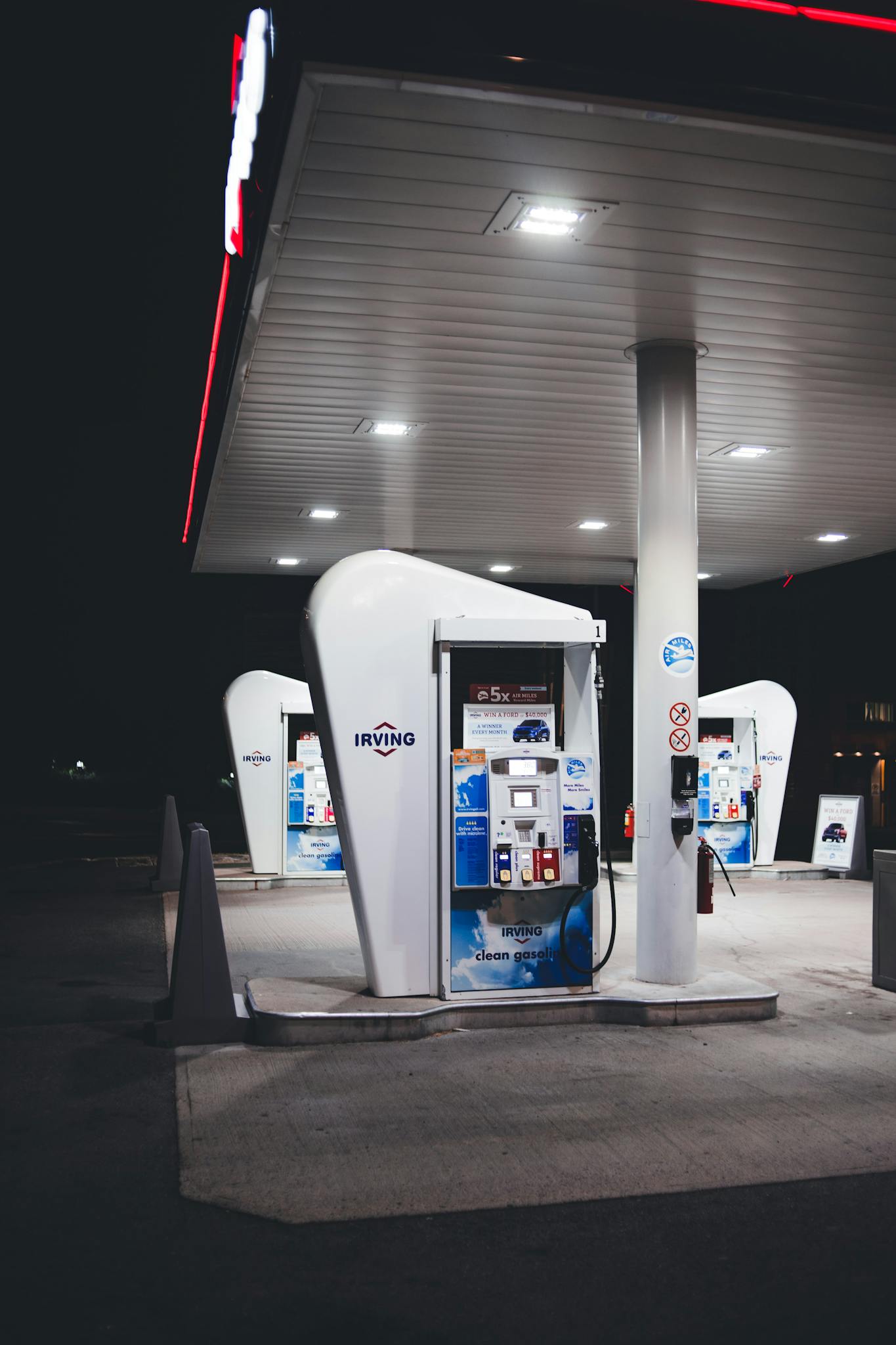 Nighttime view of a modern gas station with bright lights and fuel pumps. Ideal for urban or travel themes.