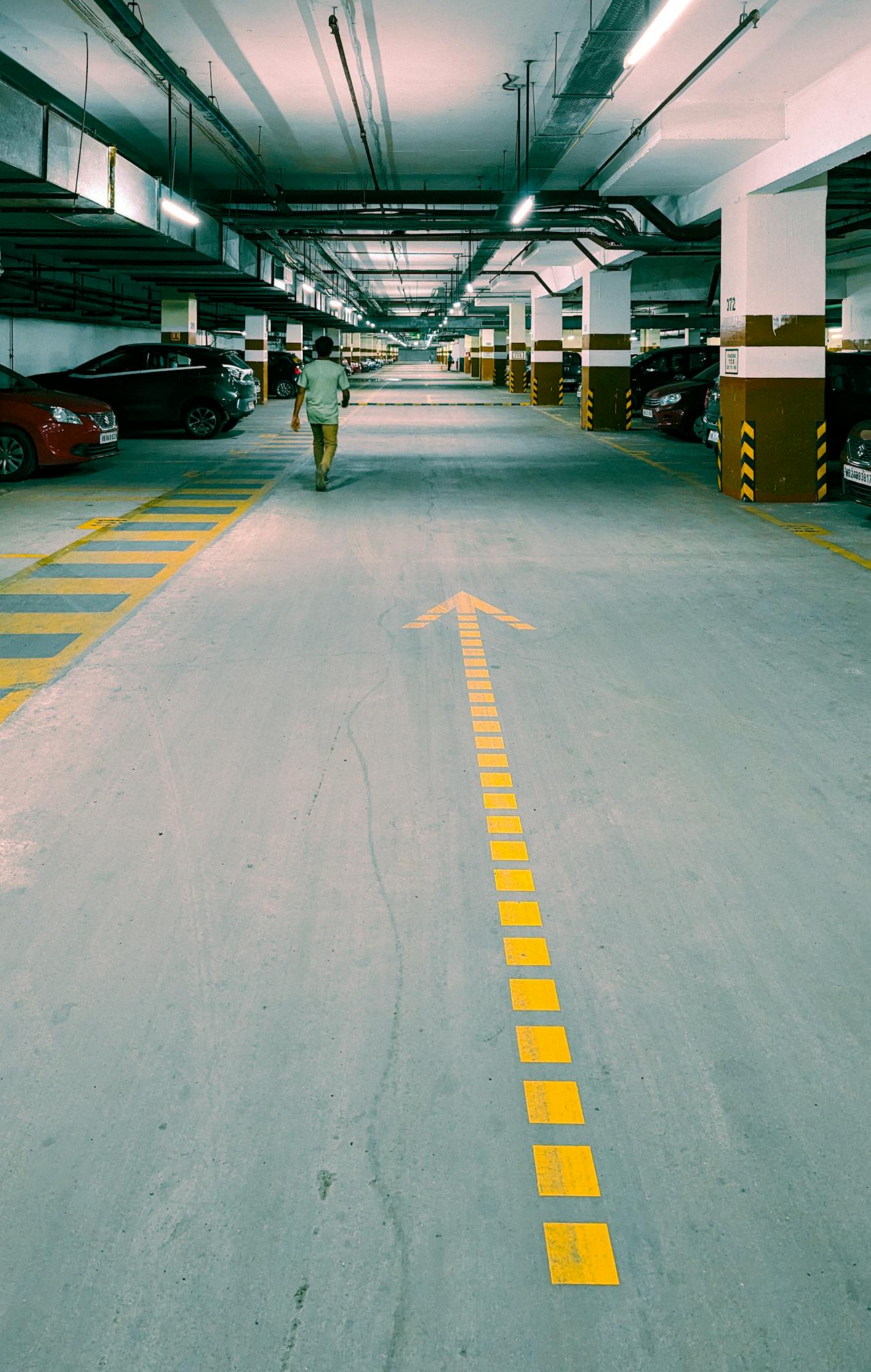 View of an underground parking lot with a clear yellow directional arrow painted on the floor.